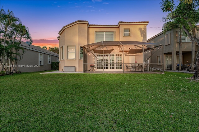 5064 SW 164th Ave, Miramar, FL 33027 - back of property at dusk with stucco siding, a patio, a tile roof, and a lawn