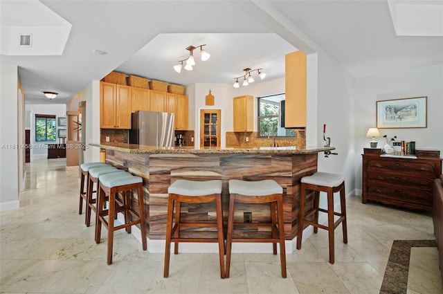 8205 SW 171st Ter, Palmetto Bay, FL 33157 - kitchen featuring freestanding refrigerator, decorative backsplash, a breakfast bar area, and a peninsula