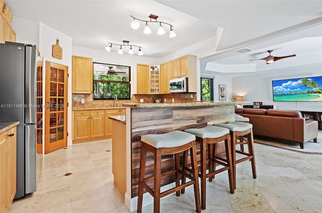 8205 SW 171st Ter, Palmetto Bay, FL 33157 - kitchen featuring stainless steel appliances, light brown cabinets, a kitchen breakfast bar, and backsplash