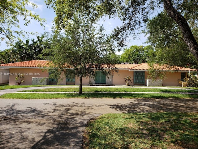 1240 La Mancha Ave, Coral Gables, FL 33134 - view of front of property with a tile roof, stucco siding, a front lawn, and curved driveway