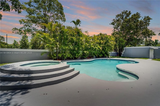 7201 SW 84th Pl, Miami, FL 33143 - pool at dusk featuring an in-ground hot tub, a patio, and view of wooded area