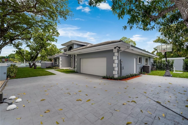 7201 SW 84th Pl, Miami, FL 33143 - view of front of house featuring a garage, central AC, driveway, a front lawn, and stucco siding
