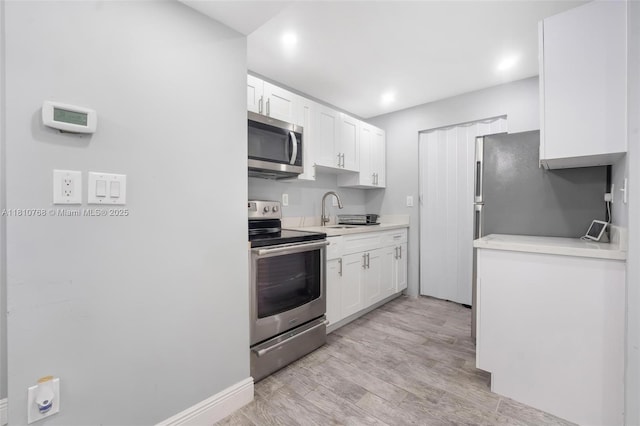 469 NE 207th Ln Unit 205, Miami, FL 33179 - kitchen with appliances with stainless steel finishes, white cabinetry, light countertops, recessed lighting, and light wood-style floors