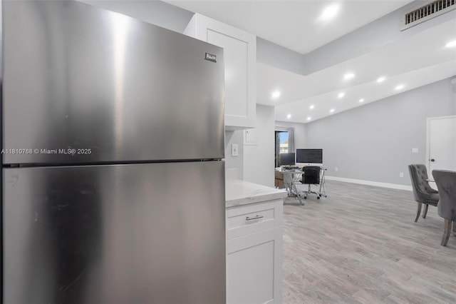 469 NE 207th Ln Unit 205, Miami, FL 33179 - kitchen with freestanding refrigerator, white cabinets, recessed lighting, light wood-style flooring, and light stone counters