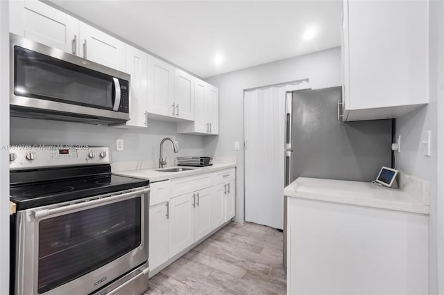 469 NE 207th Ln Unit 205, Miami, FL 33179 - kitchen with stainless steel appliances, a sink, light countertops, white cabinetry, and recessed lighting