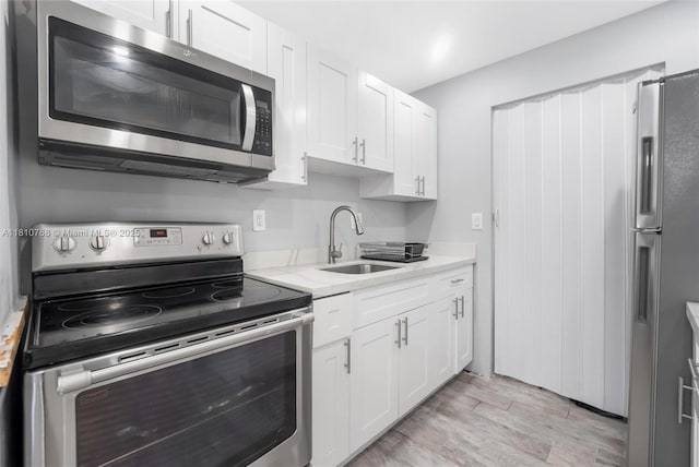 469 NE 207th Ln Unit 205, Miami, FL 33179 - kitchen with stainless steel appliances, a sink, white cabinetry, and light wood finished floors