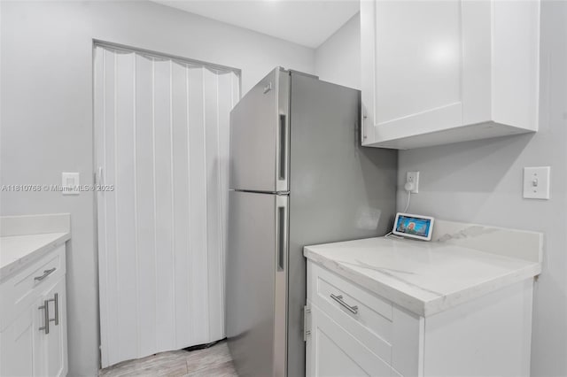 469 NE 207th Ln Unit 205, Miami, FL 33179 - kitchen with freestanding refrigerator, white cabinets, light stone countertops, and light wood-style flooring