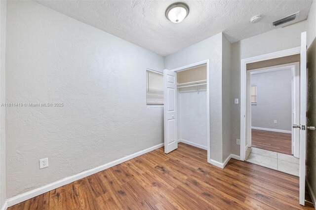 501 Carolina Ave, Fort Lauderdale, FL 33312 - unfurnished bedroom with wood finished floors, a textured wall, baseboards, a closet, and a textured ceiling