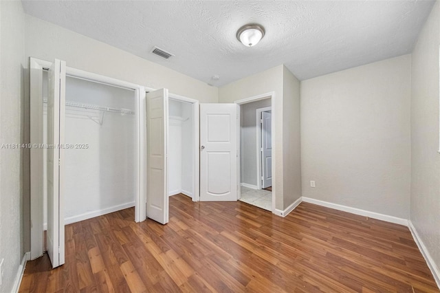 501 Carolina Ave, Fort Lauderdale, FL 33312 - unfurnished bedroom featuring wood finished floors, baseboards, a textured ceiling, and multiple closets