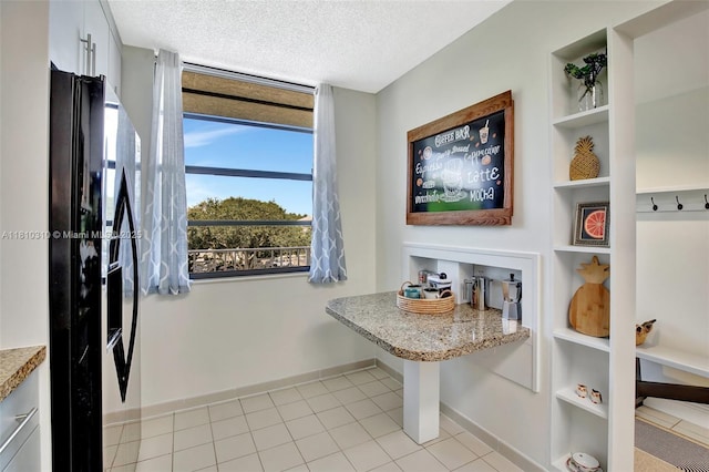 1709 Whitehall Dr Unit 401, Davie, FL 33324 - kitchen with black refrigerator with ice dispenser, baseboards, a textured ceiling, and light tile patterned flooring