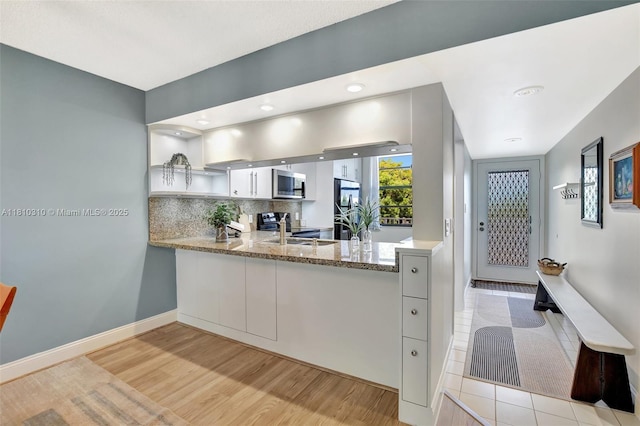 1709 Whitehall Dr Unit 401, Davie, FL 33324 - kitchen with appliances with stainless steel finishes, a sink, light wood-style floors, decorative backsplash, and light stone countertops