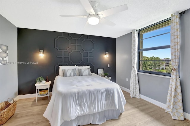1709 Whitehall Dr Unit 401, Davie, FL 33324 - bedroom featuring an accent wall, baseboards, light wood-style floors, and a ceiling fan