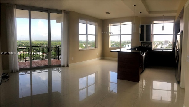 1607 Ponce De Leon Blvd Unit 12E, Coral Gables, FL 33134 - kitchen with freestanding refrigerator, light tile patterned flooring, a peninsula, and hanging light fixtures