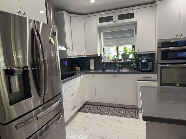 3297 W 70th St, Hialeah, FL 33018 - kitchen with appliances with stainless steel finishes, a sink, dark countertops, white cabinetry, and a textured ceiling
