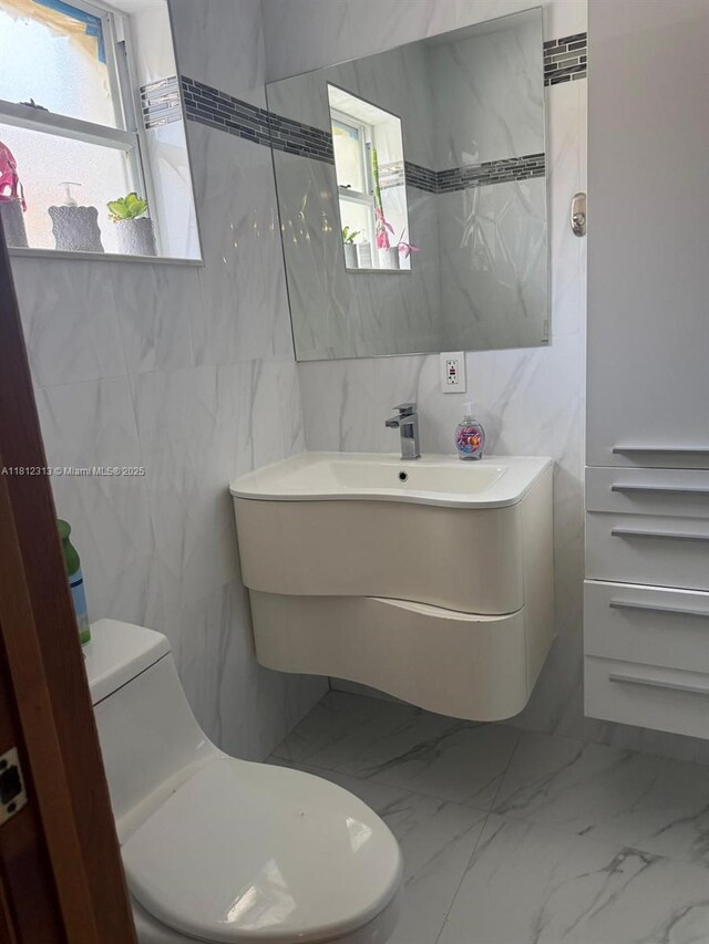 3297 W 70th St, Hialeah, FL 33018 - bathroom featuring tile walls, toilet, healthy amount of natural light, marble finish floors, and vanity