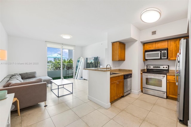 1723 SW 2nd Ave Unit 502, Miami, FL 33129 - kitchen featuring appliances with stainless steel finishes, open floor plan, a peninsula, brown cabinetry, and light tile patterned floors