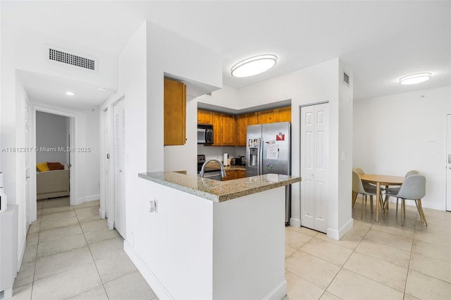 1723 SW 2nd Ave Unit 502, Miami, FL 33129 - kitchen featuring stainless steel appliances, light tile patterned floors, brown cabinets, and a peninsula