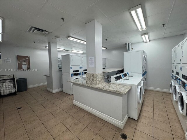 850 N Miami Ave Unit W-1903, Miami, FL 33136 - kitchen with stacked washer / drying machine, light tile patterned floors, baseboards, white cabinetry, and a paneled ceiling