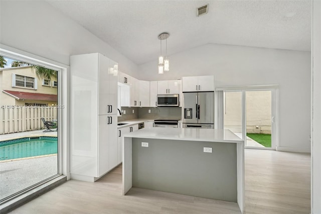 731 Briarwood Ter, Davie, FL 33325 - kitchen with stainless steel appliances, white cabinets, light wood-style floors, light countertops, and vaulted ceiling