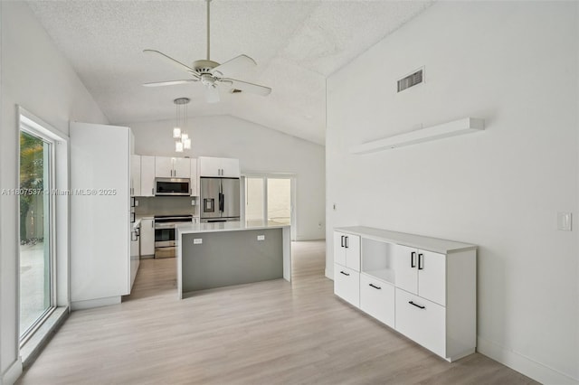 731 Briarwood Ter, Davie, FL 33325 - kitchen with stainless steel appliances, plenty of natural light, white cabinets, light wood finished floors, and lofted ceiling