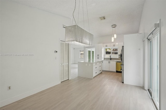 731 Briarwood Ter, Davie, FL 33325 - kitchen featuring light wood finished floors, a textured ceiling, dishwasher, white cabinetry, and light countertops