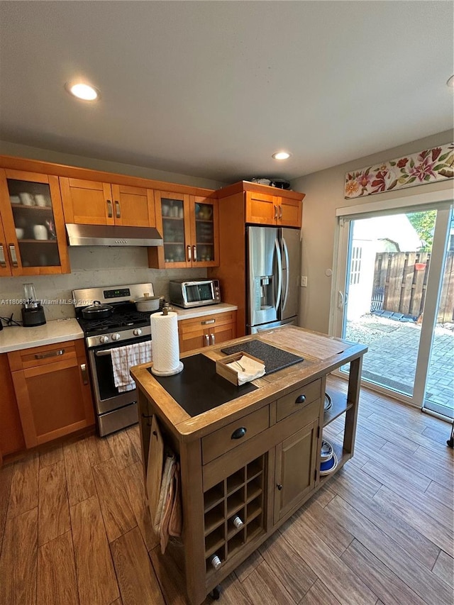 12680 SW 144th Ter, Miami, FL 33186 - kitchen with appliances with stainless steel finishes, under cabinet range hood, light wood-style floors, light countertops, and brown cabinets