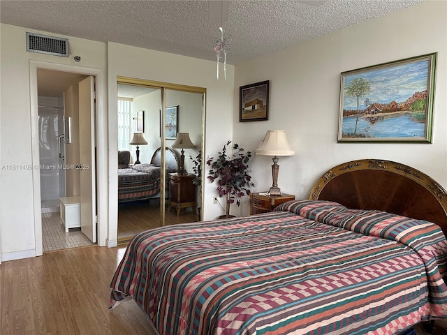 1100 NW Saint Charles Pl Unit 411, Pembroke Pines, FL 33026 - bedroom featuring wood finished floors, a closet, a textured ceiling, and ensuite bath