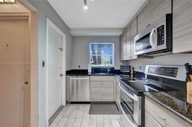 1775 N Andrews Sq Unit 104W, Fort Lauderdale, FL 33311 - kitchen featuring stainless steel appliances, light wood-style flooring, and dark stone counters
