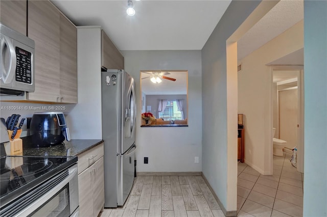 1775 N Andrews Sq Unit 104W, Fort Lauderdale, FL 33311 - kitchen featuring stainless steel appliances, ceiling fan, dark stone countertops, and light wood-style floors