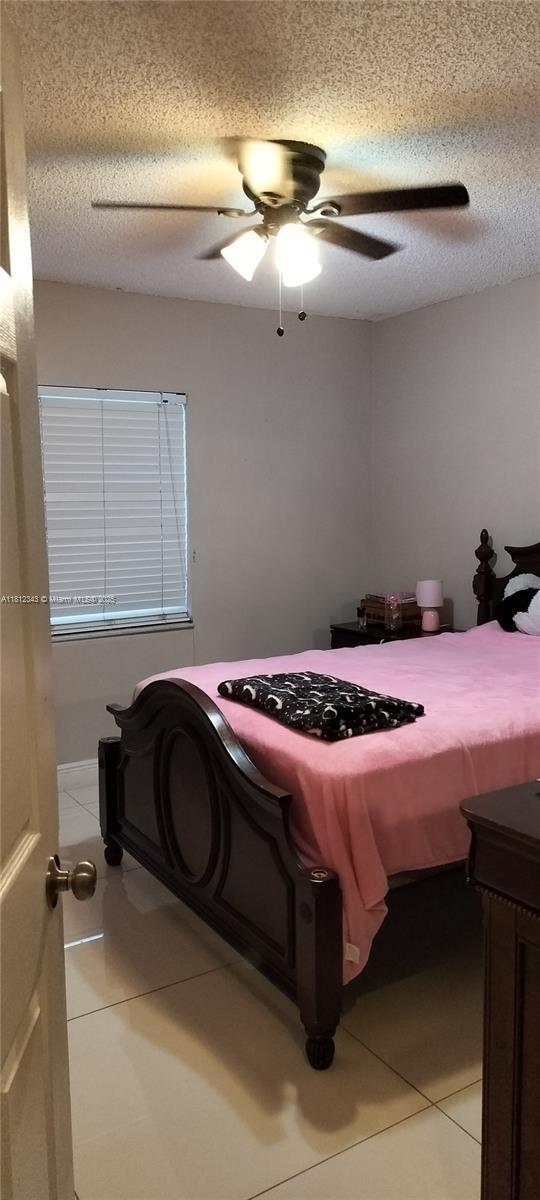 3149 W 68th Pl, Hialeah, FL 33018 - bedroom with light tile patterned floors, a textured ceiling, and a ceiling fan