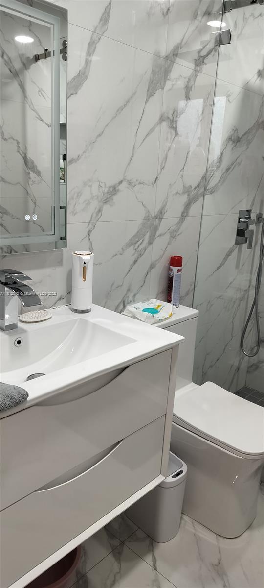 3149 W 68th Pl, Hialeah, FL 33018 - bathroom with a marble finish shower, marble finish floors, vanity, toilet, and tile walls