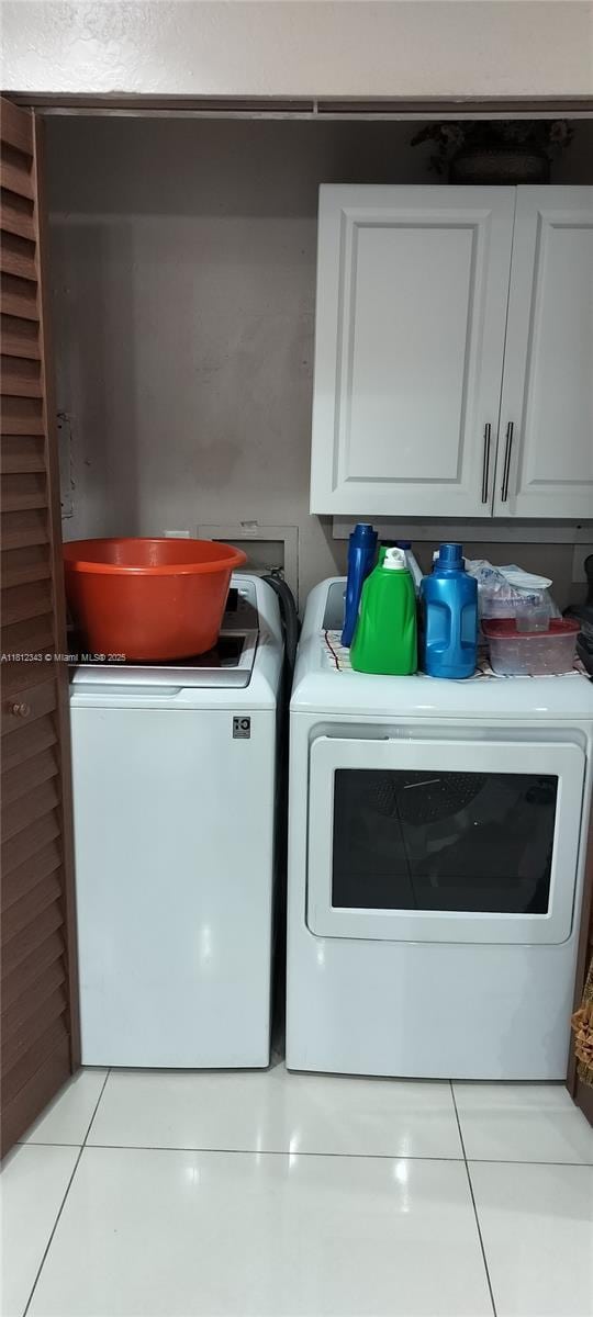 3149 W 68th Pl, Hialeah, FL 33018 - washroom with cabinet space, washer and dryer, and light tile patterned flooring