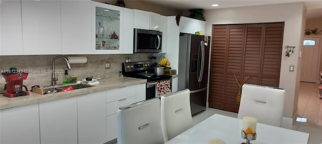 3149 W 68th Pl, Hialeah, FL 33018 - kitchen with appliances with stainless steel finishes, tasteful backsplash, a sink, light countertops, and white cabinets