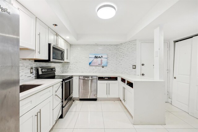 1351 NE Miami Gardens Dr Unit 1111E, Miami, FL 33179 - kitchen featuring stainless steel appliances, a tray ceiling, light tile patterned floors, and decorative backsplash