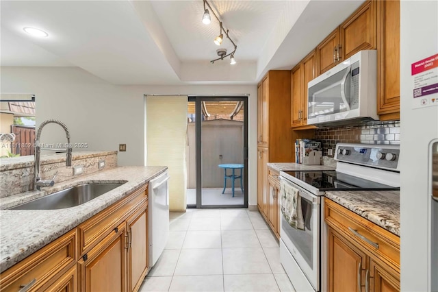 3003 30th Ln, Green Acres, FL 33463 - kitchen with white appliances, brown cabinetry, backsplash, light stone countertops, and light tile patterned floors