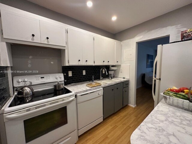 2181 NE 67th St Unit 628, Fort Lauderdale, FL 33308 - kitchen featuring white appliances, light countertops, backsplash, light wood finished floors, and white cabinets