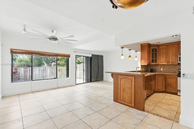 4225 N 76th Ave, Davie, FL 33024 - kitchen with a peninsula, brown cabinetry, glass insert cabinets, decorative backsplash, and light tile patterned floors