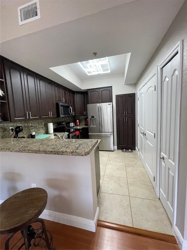 8980 W Flagler St Unit 202, Miami, FL 33174 - kitchen with stainless steel appliances, a peninsula, dark brown cabinets, tasteful backsplash, and a tray ceiling