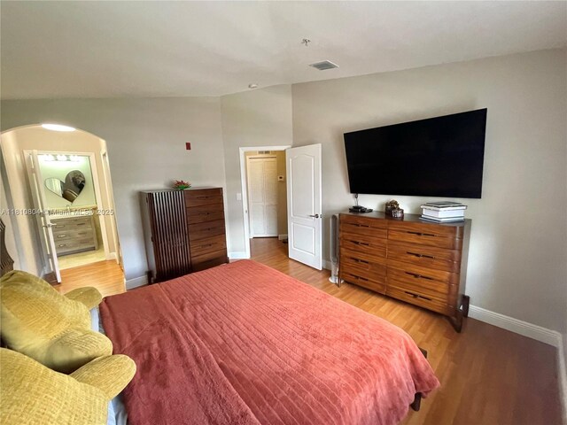 8980 W Flagler St Unit 202, Miami, FL 33174 - bedroom with baseboards, light wood-style floors, arched walkways, lofted ceiling, and ensuite bathroom