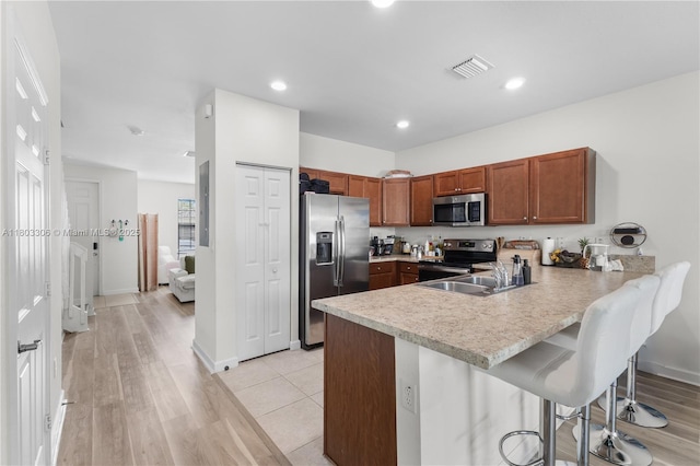 9214 W 33rd Ln, Hialeah, FL 33018 - kitchen featuring stainless steel appliances, a peninsula, light countertops, a breakfast bar, and brown cabinetry