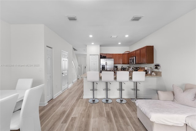 9214 W 33rd Ln, Hialeah, FL 33018 - kitchen featuring stainless steel appliances, a peninsula, a breakfast bar area, light wood finished floors, and recessed lighting