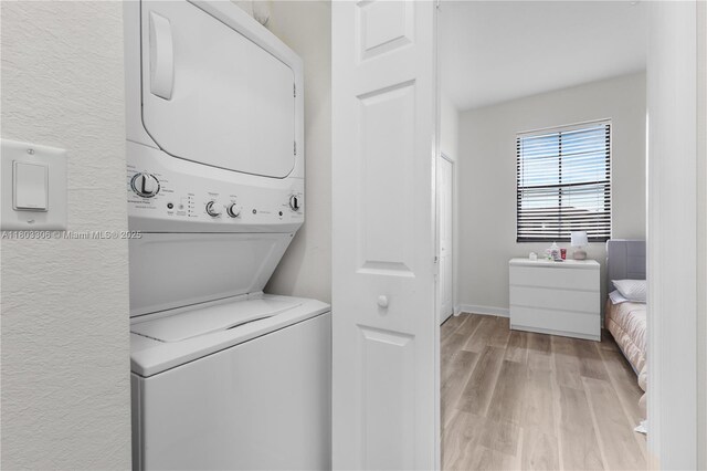 9214 W 33rd Ln, Hialeah, FL 33018 - laundry room featuring stacked washer and clothes dryer, light wood-type flooring, baseboards, and a textured wall