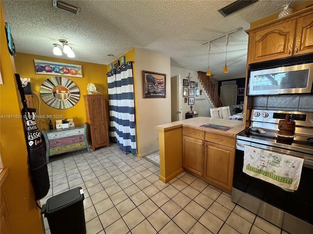 10428 NW 3rd St, Pembroke Pines, FL 33026 - kitchen with appliances with stainless steel finishes, a peninsula, brown cabinetry, light tile patterned floors, and a textured ceiling