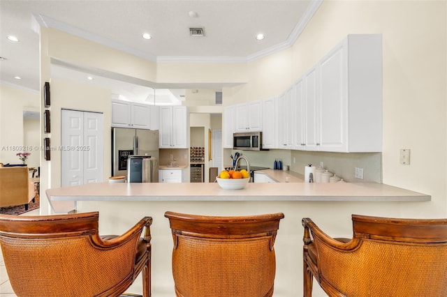 1220 Iris Ct, Weston, FL 33326 - kitchen with stainless steel appliances, a peninsula, ornamental molding, light countertops, and white cabinetry
