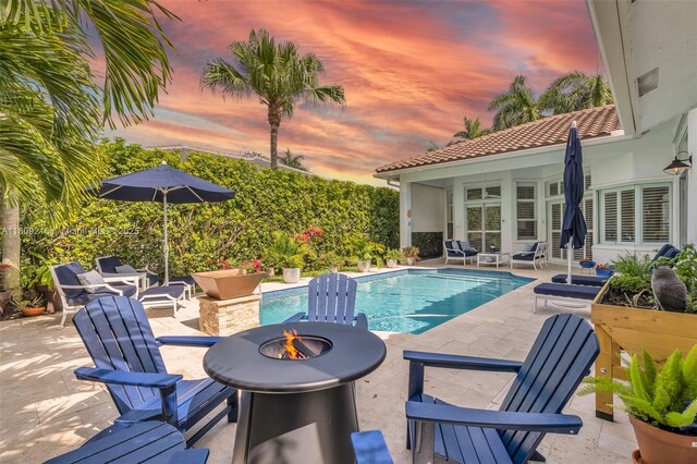 1220 Iris Ct, Weston, FL 33326 - pool at dusk featuring an outdoor fire pit and a patio