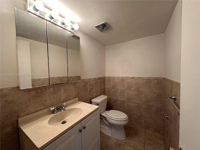 1130 11th St Unit 4J, Miami Beach, FL 33139 - half bathroom with tile walls, toilet, vanity, a wainscoted wall, and tile patterned floors