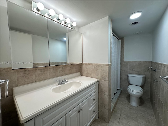 1130 11th St Unit 4J, Miami Beach, FL 33139 - bathroom featuring tile walls, toilet, vanity, a wainscoted wall, and tile patterned flooring
