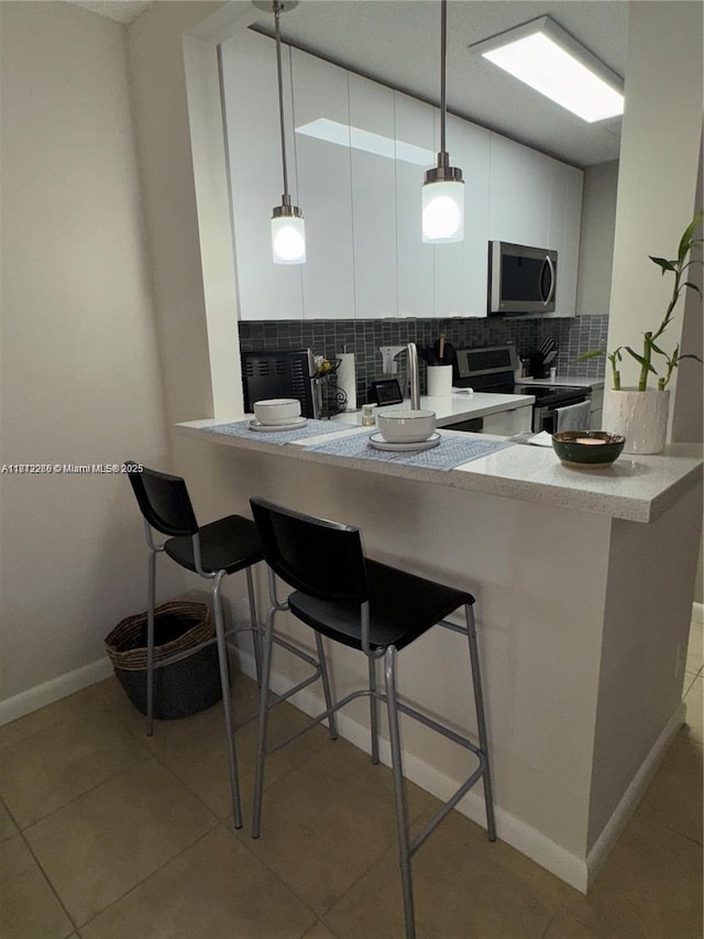 3586 N University Dr Unit U-6, Coral Springs, FL 33065 - kitchen featuring stainless steel appliances, tasteful backsplash, white cabinetry, a peninsula, and a kitchen breakfast bar
