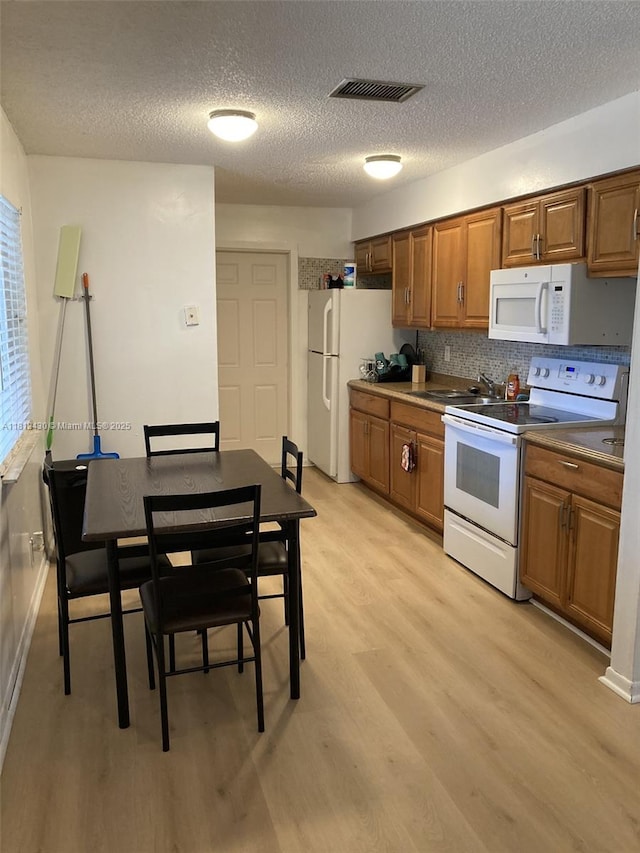 6132 SW 39th St, Miramar, FL 33023 - kitchen with white appliances, brown cabinetry, light wood finished floors, a textured ceiling, and backsplash