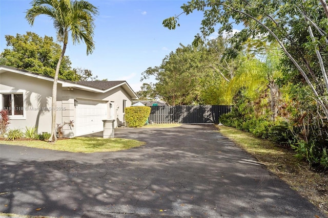 17243 SW 87th Ave, Palmetto Bay, FL 33157 - view of side of home with asphalt driveway, an attached garage, and stucco siding